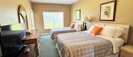 Una habitación de hotel con dos camas, un escritorio, un televisor y una ventana.