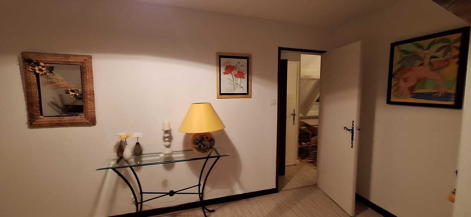 A hallway with a glass console table, a lamp, a mirror, and framed artwork on the walls.