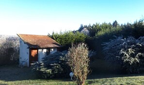 A small white building with a brown roof, surrounded by trees and shrubs. - Charming Country Home (Villebret)