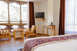 Habitación de hotel con cama, escritorio con cafetera, televisor y silla.