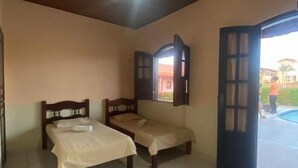 Habitació amb dos llits, ventilador al sostre i vista exterior.