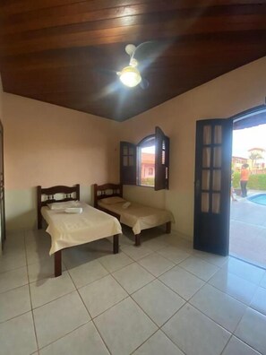 A room with two beds, a ceiling fan, and a view of the outside. - Pousada Caranà (Salinópolis)