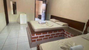Habitació amb dos llits, un frigorífic i una paret de maó.