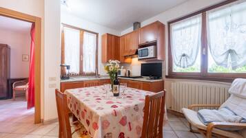 Une cuisine compacte avec des meubles en bois, un four à micro-ondes et un coin repas avec une table dressée pour deux personnes.