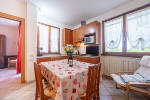 Eine kompakte Küche mit Holzschränken, einer Mikrowelle und einem Essbereich mit Tisch für zwei Personen.