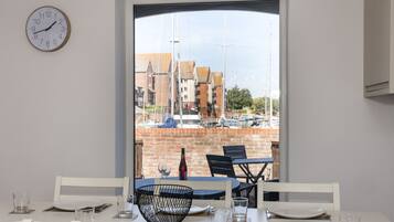 A dining area with a view of a marina, a clock on the wall, and a brick wall.