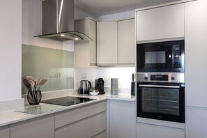 A modern kitchen with a built-in microwave, oven, and coffee maker. - Harbourside Haven - stylish marina living (Eastbourne)