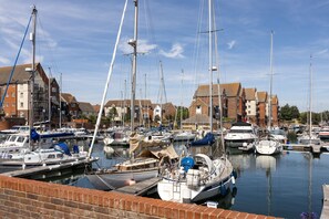 A marina with multiple boats docked, surrounded by residential buildings. - Harbourside Haven - stylish marina living (Eastbourne)