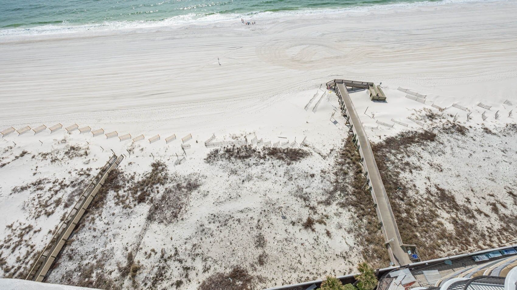 Ein Strand mit einer Holzpromenade, die zu einem Steg führt.
