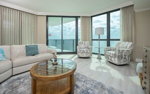 A modern living room with a sofa, armchairs, a coffee table, and a view of the sea through large windows. - Phoenix Ix 1407 2 Bedroom Condo (Orange Beach)