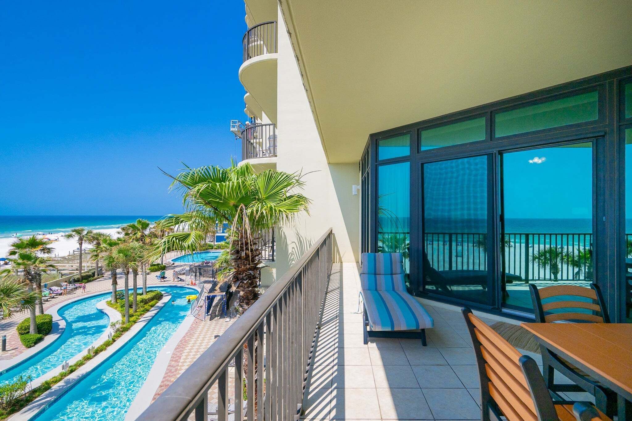 A balcony with a view of a swimming pool and beach.