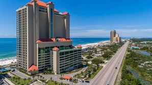 A high-rise hotel with a red roof, a beach view, and a road leading to the beach. - Phoenix West 307 3 Bedroom Condo (Orange Beach)