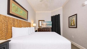 A hotel room with a large bed, a headboard with a woven design, a flat-screen TV, a dresser, and artwork on the walls. - Phoenix West 307 3 Bedroom Condo (Orange Beach)