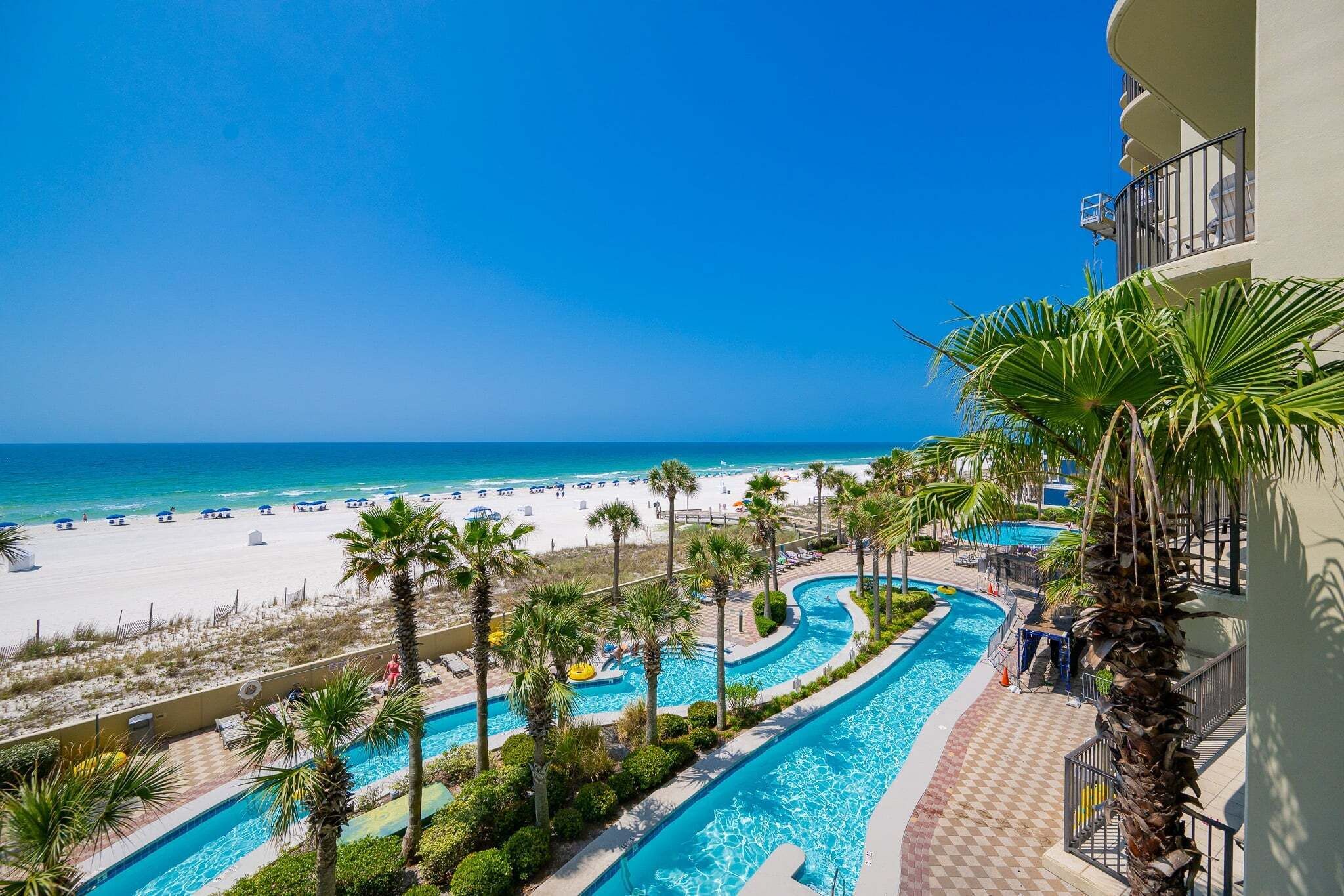 A resort with a pool area, a beach, and a view of the ocean.