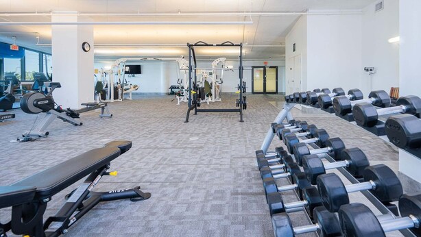 A gym with various exercise equipment, including dumbbells, benches, and weight machines. - Phoenix West 307 3 Bedroom Condo (Orange Beach)