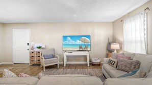 Ein Wohnzimmer mit Fernseher, einer Couch, einem Sessel und einem kleinen Tisch.