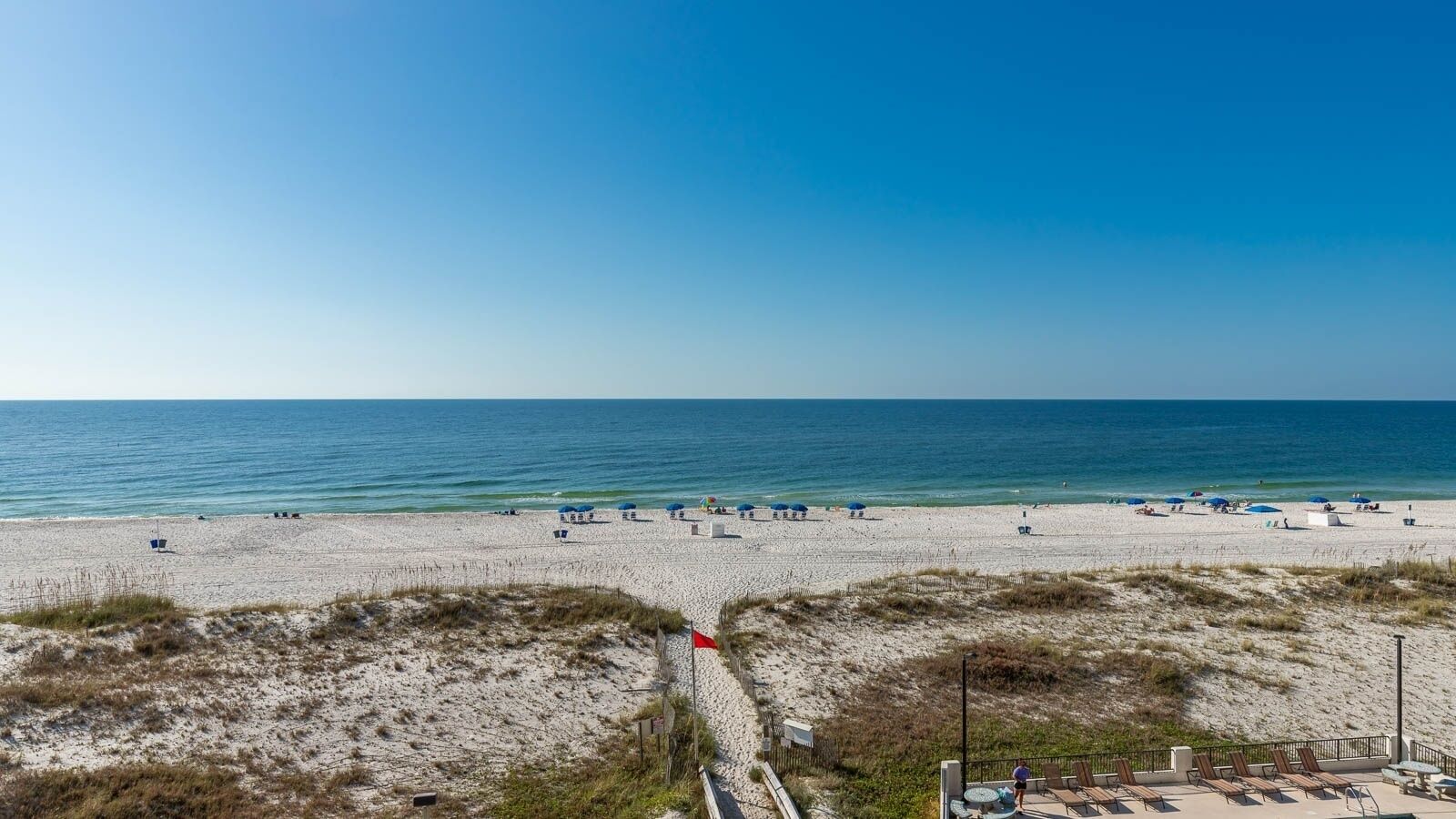Ein Strand mit blauem Himmel, sandigem Ufer und Sonnenschirmen.