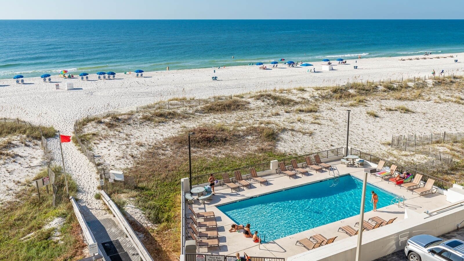 Un hôtel situé en bord de mer, doté d’une piscine, de parasols et d’une plage de sable.