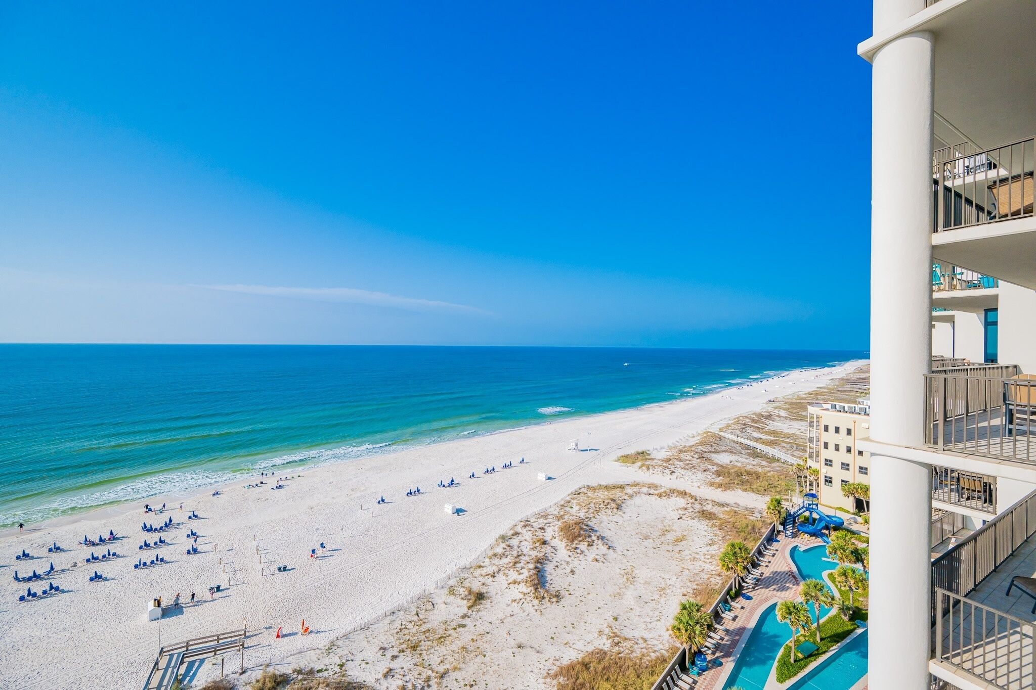 A beach with a pool and a building with balconies.
