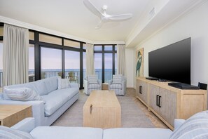 A modern living room with a sofa, chairs, a coffee table, and a TV. - The Oasis 1008 Formerly Phoenix West Ii 1008 3 Bedroom Condo (Orange Beach)