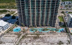 Ein Hochhaus mit mehreren Balkonen, einem Poolbereich und einem Strand.