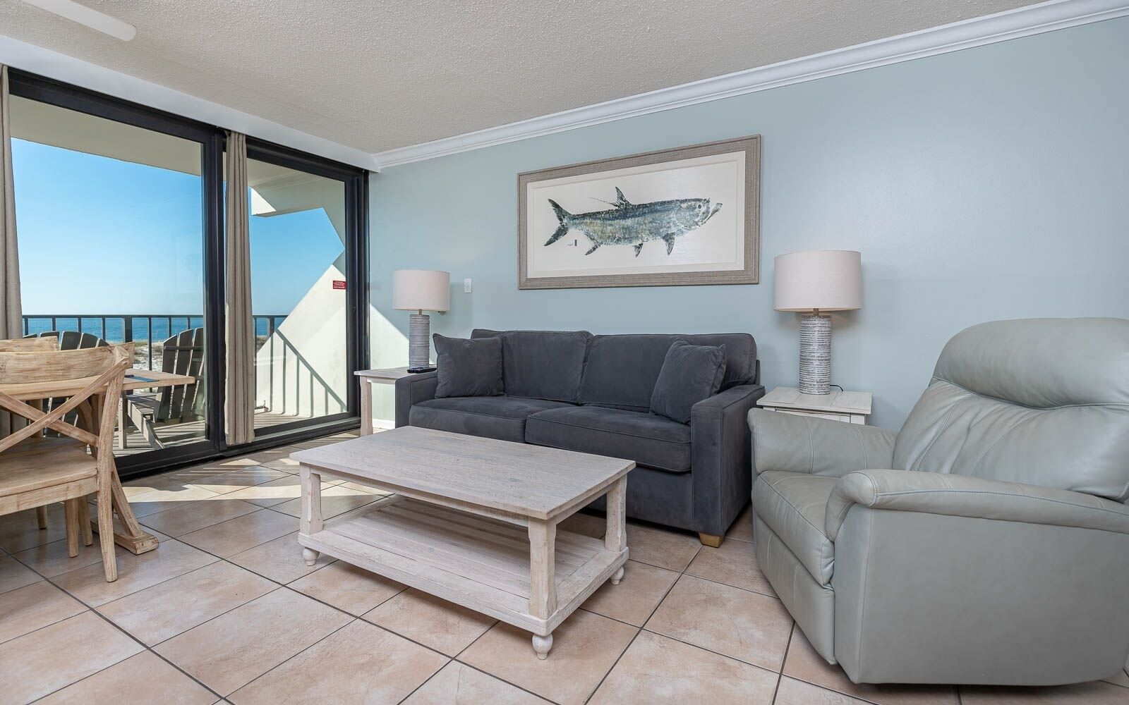 A living room with a sofa, a chair, a coffee table, and a painting of a fish on the wall.