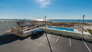 Un estacionamiento con zona de piscina, un área de descanso cubierta y vista a la playa.