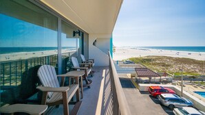 A balcony with a view of the beach, outdoor seating, and a parking area. - Island Winds East 309 2 Bedroom Condo (Gulf Shores)