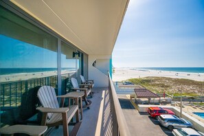 A balcony with a view of the beach, outdoor seating, and a parking area. - Island Winds East 309 2 Bedroom Condo (Gulf Shores)