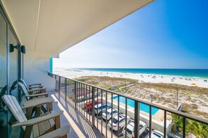Ein Balkon mit Blick auf einen Strand und ein Schwimmbad.
