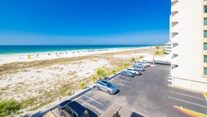 A beachfront hotel with a parking lot and beach view. - Island Winds East 309 2 Bedroom Condo (Gulf Shores)