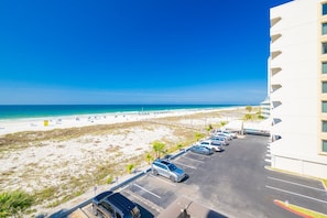 A beachfront hotel with a parking lot and beach view. - Island Winds East 309 2 Bedroom Condo (Gulf Shores)