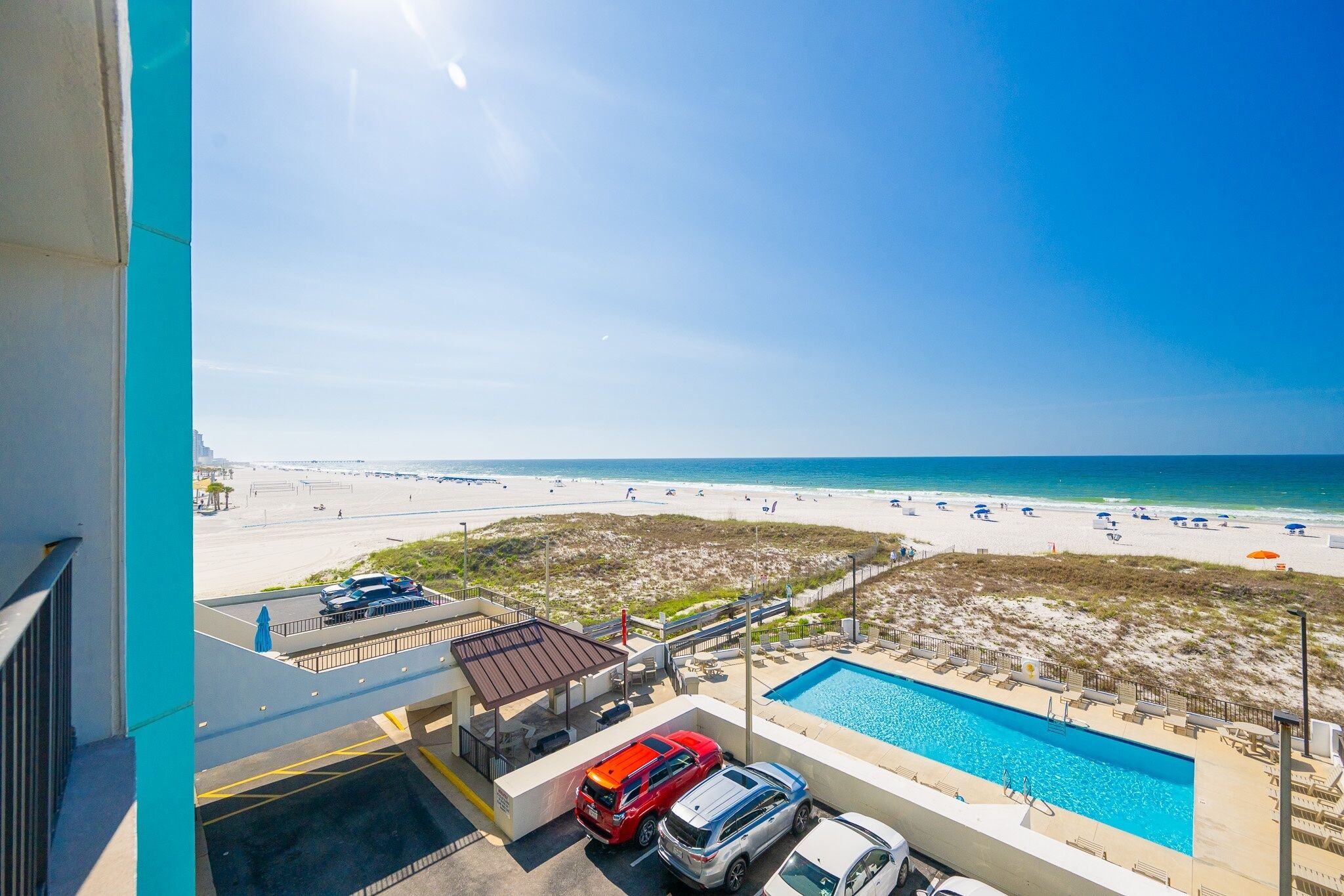 Blick auf ein Schwimmbecken mit einem klaren Strand und dem Meer im Hintergrund.