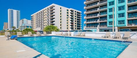 Une piscine équipée de chaises longues et d’un panneau indiquant les règles d’utilisation.