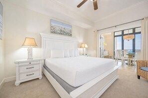 A hotel room with a large bed, two bedside tables with lamps, a painting on the wall, and a view through a glass door. - The Oasis 706 Formerly Phoenix West Ii 706 3 Bedroom Condo (Orange Beach)