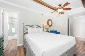 A bedroom with a bed, a ceiling fan, a lamp, and a door. - Island Winds East 708 2 Bedroom Condo (Gulf Shores)