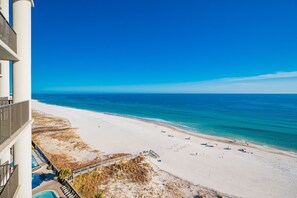 A beach with a clear view of the ocean, a sandy shore, and a building with a balcony overlooking the beach. - The Oasis 1003 Formerly Phoenix West Ii 1003 3 Bedroom Condo (Orange Beach)