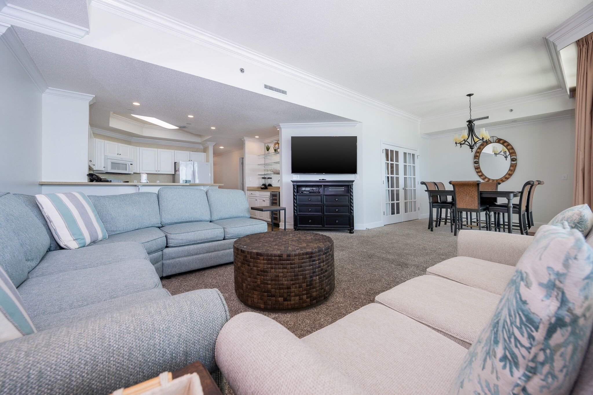 A spacious living room with a sofa set, a coffee table, and a dining area with chairs and a table.