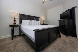 Un dormitorio con cama, dos mesitas de noche, un aparador y una televisión.