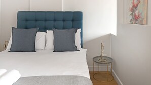 A bedroom with a bed, pillows, a bedside table, and a wall-mounted artwork. - Stylish Roof Top Pool Studio Apartment The Tokyo (Cape Town)