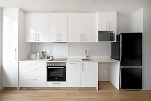 Eine moderne Küche mit weißen Schränken, einem Backofen von Bosch, einem schwarzen Kühlschrank und einer Mikrowelle.