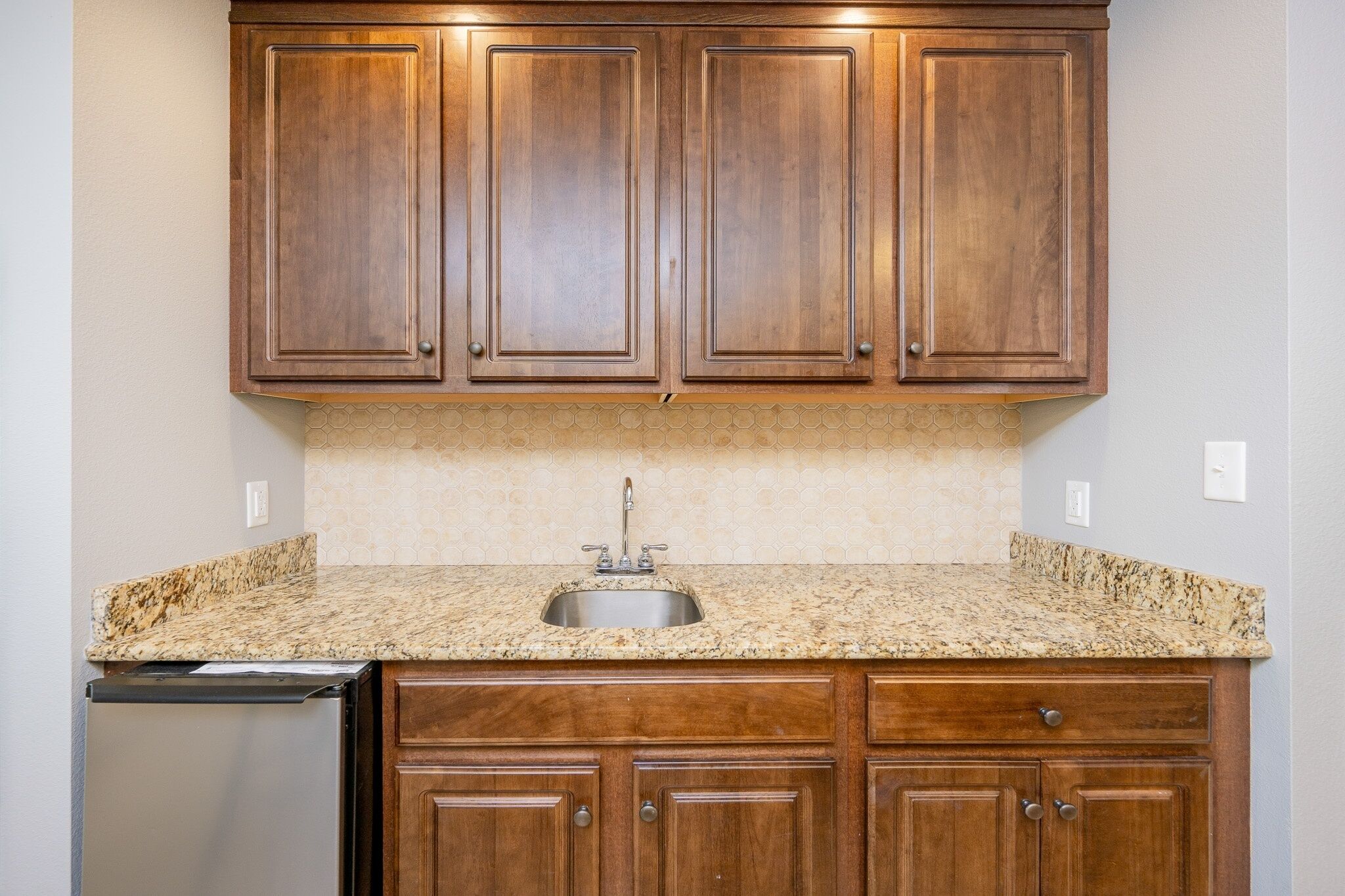 A kitchen with wooden cabinets, a granite countertop, and a stainless steel sink.