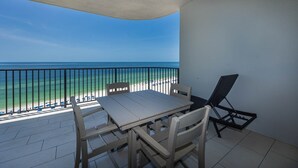 Ein Balkon mit Tisch und Stühlen, mit Blick auf einen Strand und einen freien Blick auf das Meer.