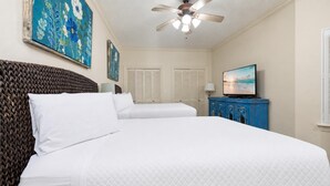 Ein Hotelzimmer mit einem großen Bett, einem Deckenventilator, einem Fernseher und Kunstwerken an den Wänden.