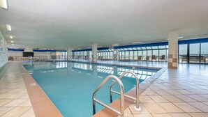 Ein beheiztes Hallenbad mit klarem, blauem Wasser, Fliesenboden und einer Metallleiter.