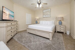 A bedroom with a bed, a dresser, a television, a ceiling fan, and two bedside lamps. - Phoenix Ix 902 2 Bedroom Condo (Orange Beach)