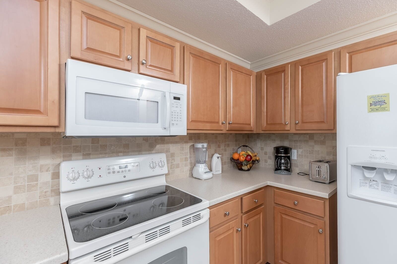A kitchen with wooden cabinets, a white microwave, a stove, a toaster, and a refrigerator.