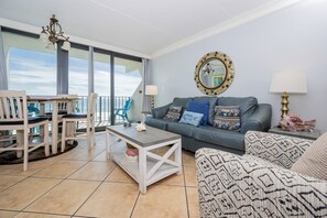 Ein Wohnzimmer mit Balkon, einer Couch, einem Couchtisch und einem Essbereich mit Stühlen.
