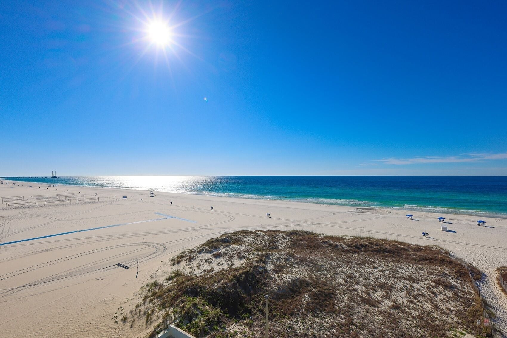 Una playa con cielos despejados, una orilla arenosa y algunas sombrillas.