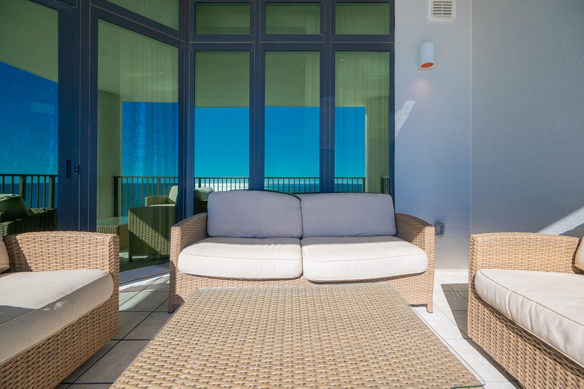 A balcony with wicker furniture and a view of the ocean.